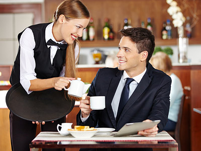 Eine Kellnerin serviert einem Mann Kaffee in einem Restaurant.