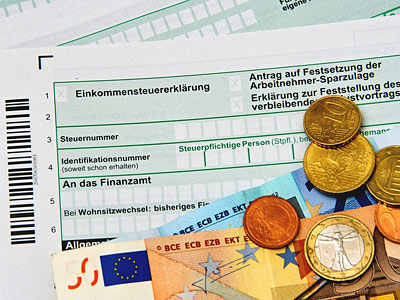 Einkommensteuererklärung mit Euro-Banknoten und Münzen.